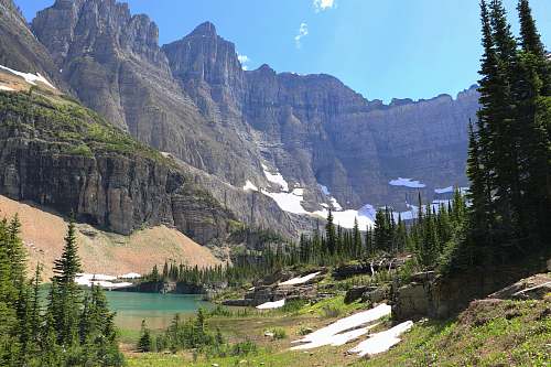mountain mountains near trees and body of water at daytime glacier national park